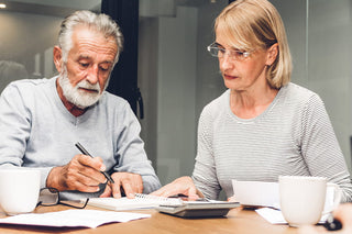 Senior couple reviewing paperwork and a calculator while comparing online casket options
